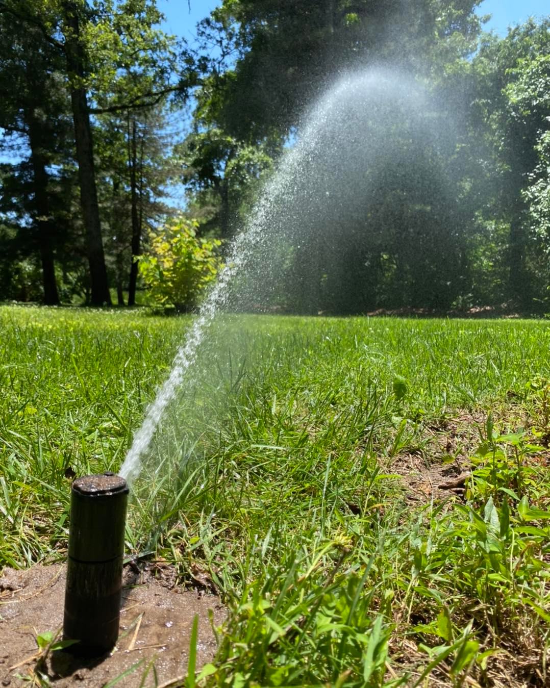 Sprinkler head spraying a field in Broken Arrow after a Sprinkler System Repair by Rockwell Irrigation and Landscaping